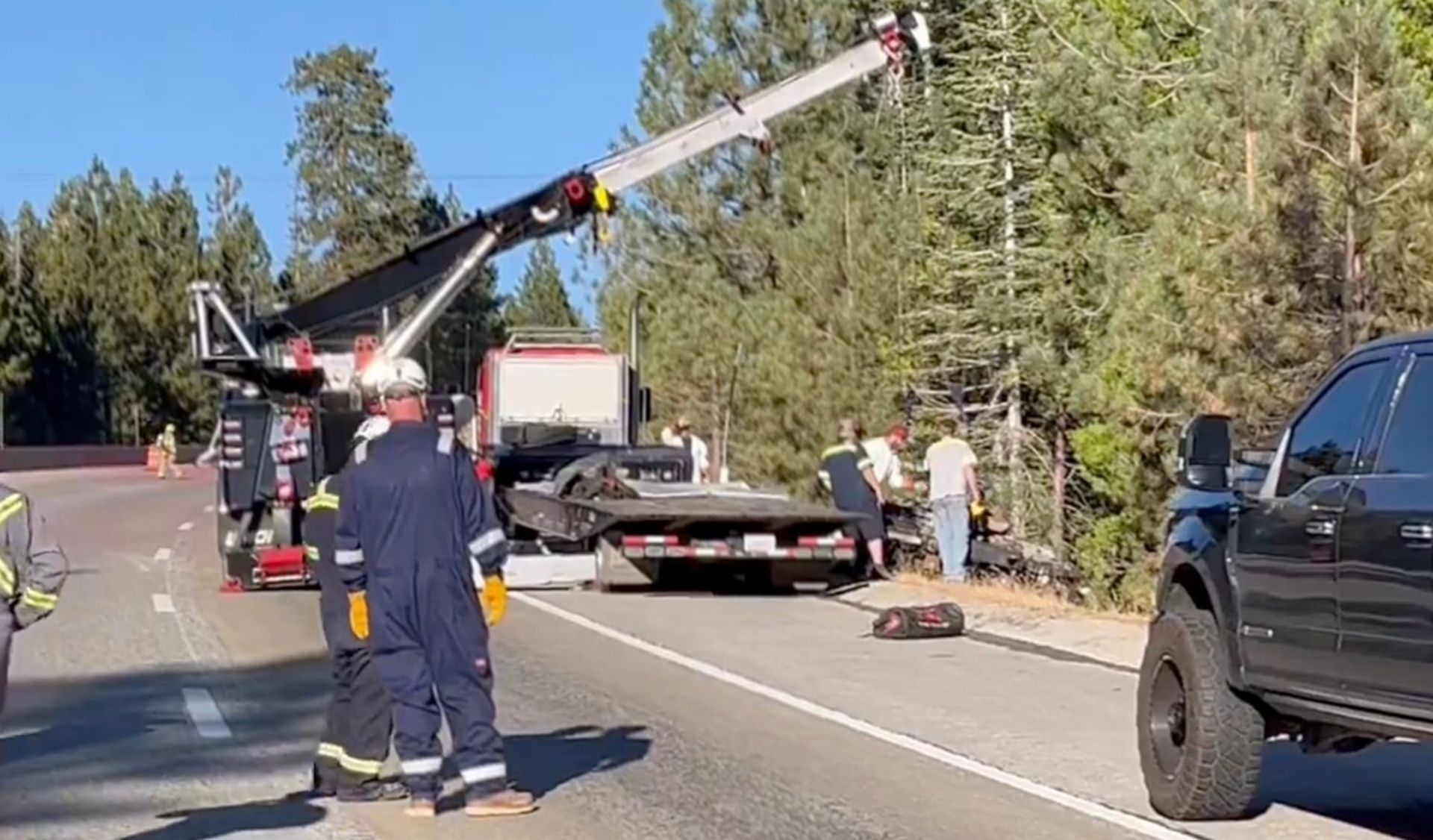 Fire crews and hazardous materials management team next to a crane, a truck and a van