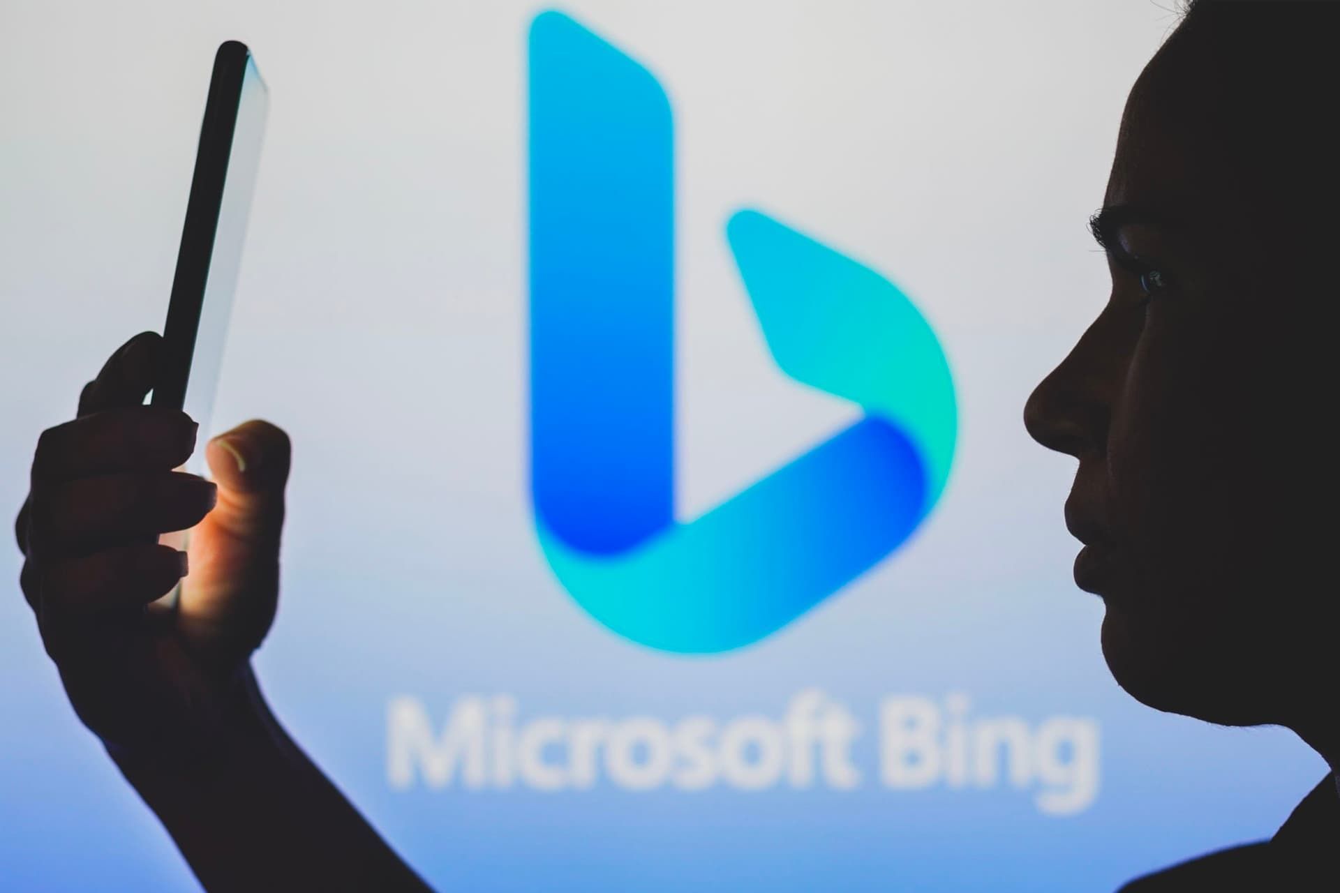 A woman with a mobile phone in front of the Microsoft Bing logo